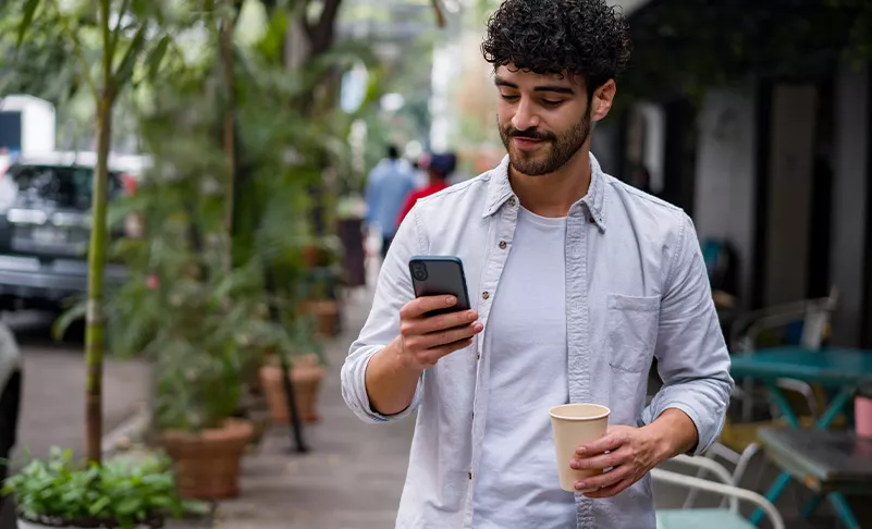 guy walking with smartphone and coffee