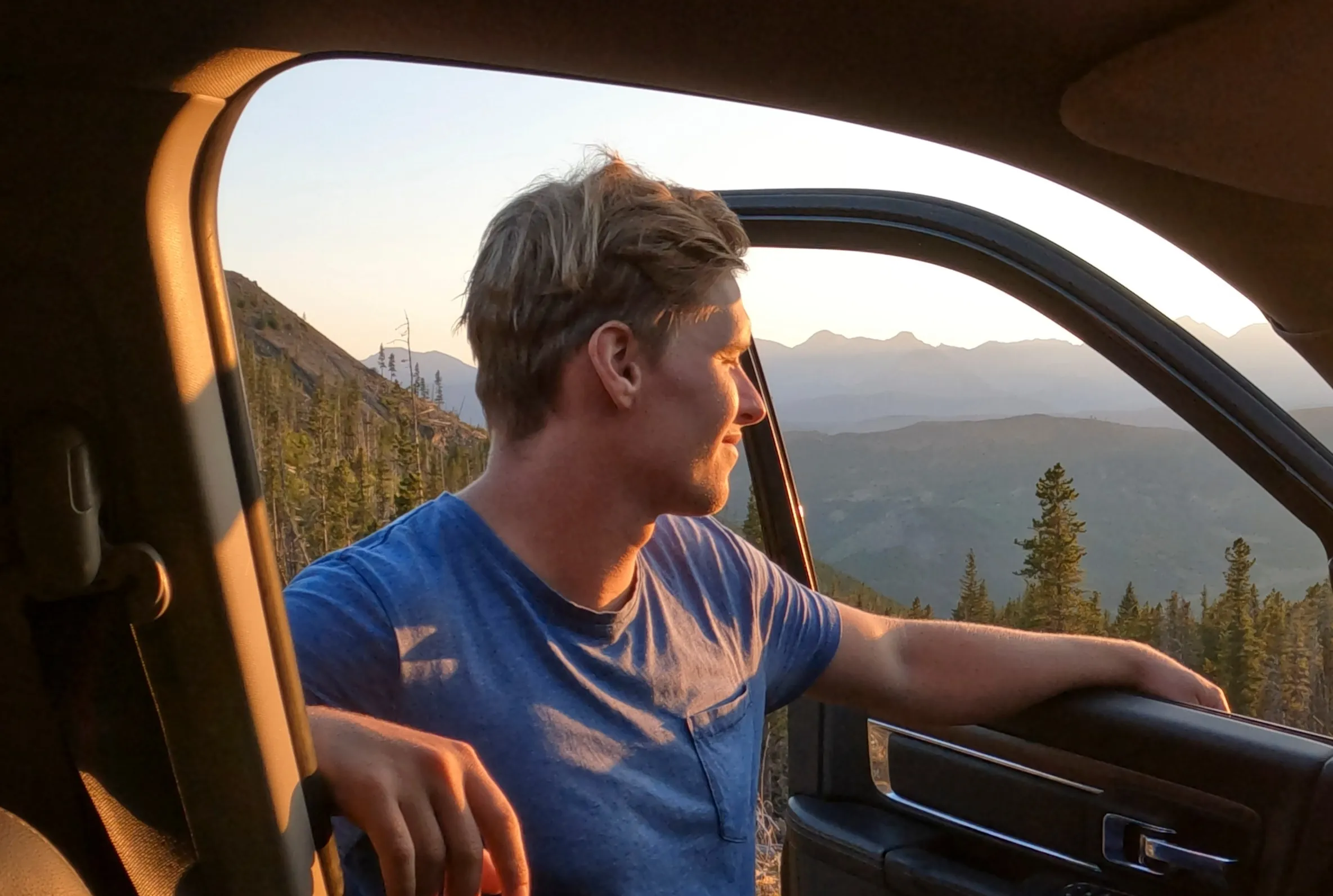 man standing outside car looking at the sunset